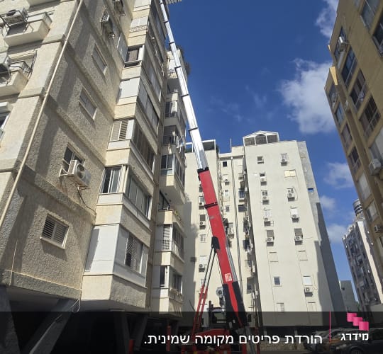 מנוף אדום ליד בניין גבוה בשטח חניה